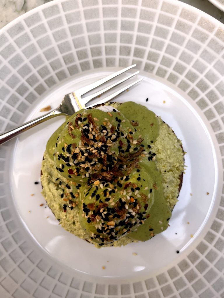 Smashed broad beans covering a bagel and a poached egg